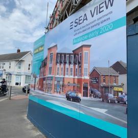 Image of hoarding and artists impression of new building